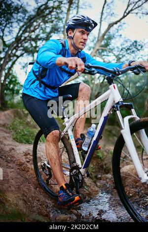 Tough terrain for a tough man. Shot of a male cyclist riding along a mountain bike trail. Stock Photo