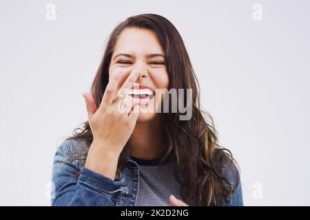 Give yourself the giggles. Studio shot of a young woman making a funny face against a gray background. Stock Photo