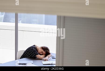 I need a long nap. Shot of a young businesswoman taking a nap in her office. Stock Photo