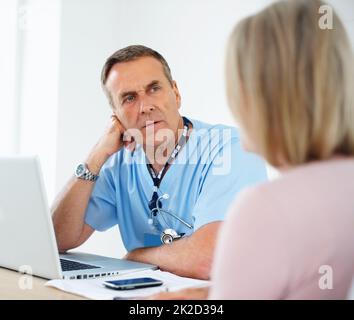Serious medical doctor listening to female patient at clinic. Portrait of a serious medical doctor listening to female patient at clinic. Stock Photo