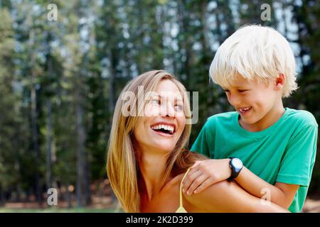 Mother giving piggyback ride to her son. Beautiful woman giving a piggyback ride to her son during holiday. Stock Photo