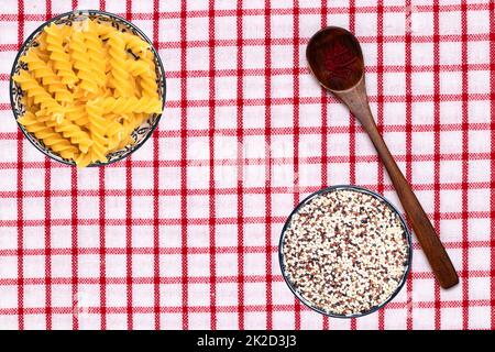 Vegetable food. Closeup of two bowls with noodles and quinoa and a spoon with safran spice threads on a tablecloth. Healthy eating and nutrition. Top view with space. Stock Photo