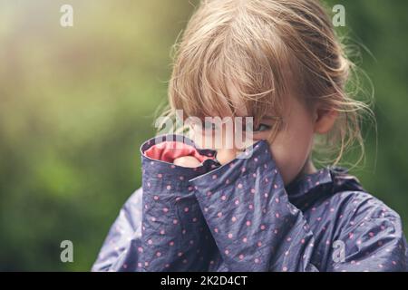 Shes a shy cutie pie. Shot of a shy little girl standing outside. Stock Photo