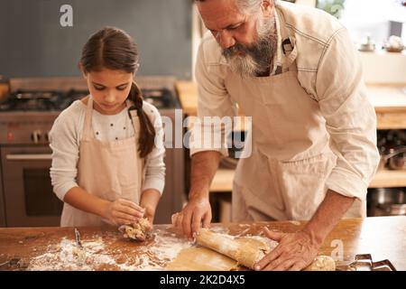Theyre serious about baking. Shot of a girl and her grandfather baking together in the kitchen. Stock Photo