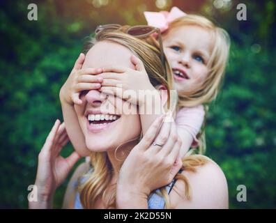 Peek a boo, guess who. Shot of an adorable little girl playfully covering her mothers eyes outdoors. Stock Photo