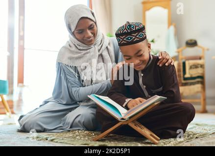 Love is the supreme form of communication. Shot of a young muslim mother and her son reading in the lounge at home. Stock Photo