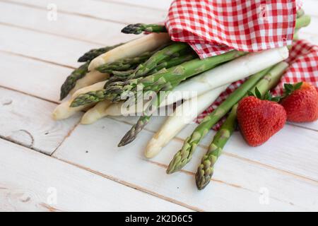 Asparagus with strawberries on white wood Stock Photo