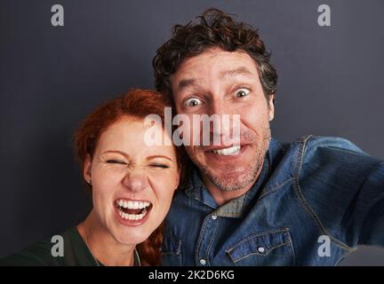 Winners of the couples silly face competition. Portrait of a happy young couple pulling silly faces for a selfie. Stock Photo