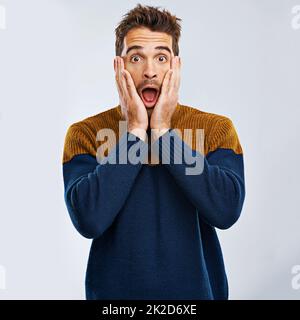 I cant believe it. Portrait of a handsome man expressing surprise against a gray background. Stock Photo