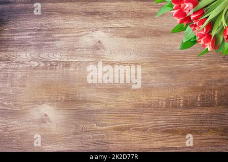 Colorful red tulips on rustic wooden table with copy space. Fresh spring flowers on planks. Greeting card. Valentine, birthday, mothers or wedding day.Top view. Stock Photo