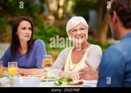 Good food and great conversation. Shot of a mother having lunch outside with her adult son and daughter. Stock Photo