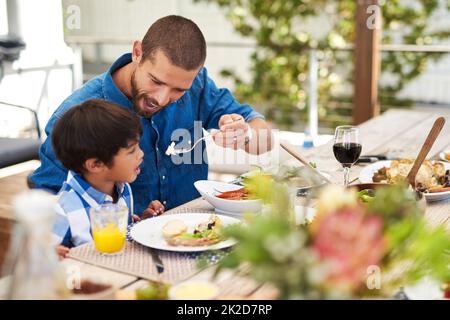 Dining with my little champ. Shot of a father feeding his young son while having a meal together outdoors. Stock Photo