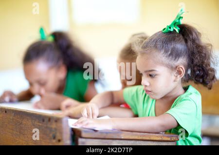 Eager to work and learn - Young minds. Cute little preschoolers sitting in a classroom and drawing together. Stock Photo