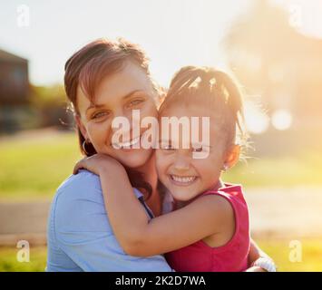 Quality time with mom. Portrait of a smiling mother hugging her little daughter while enjoying a day together in the park. Stock Photo