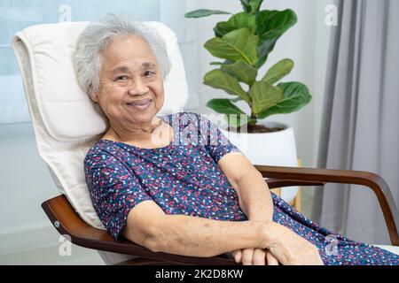 Asian elderly woman sitting and relaxing with happy in rocking chair at room in home. Stock Photo