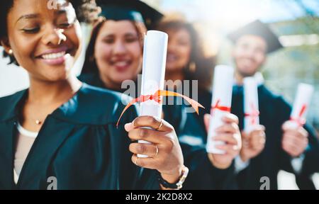 This is our ticket to success. Cropped shot of a group of students holding their diplomas on graduation day. Stock Photo