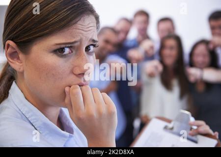 What do I do now. Closeup of an anxious young woman facing the accusatory fingers of her coworkers. Stock Photo