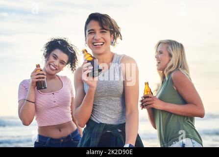 We bring the party wherever we go. Shot of three friends enjoying drinks while on the beach. Stock Photo