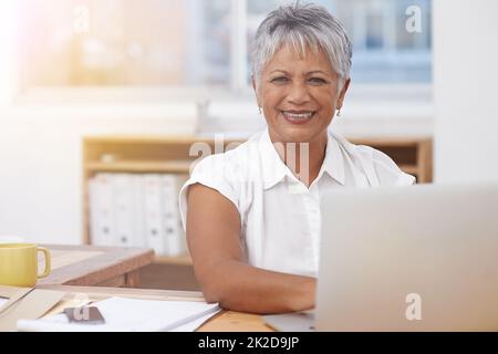 Tackling her work with a can-do attitude. Portrait of a mature businesswoman working on her laptop at her desk. Stock Photo