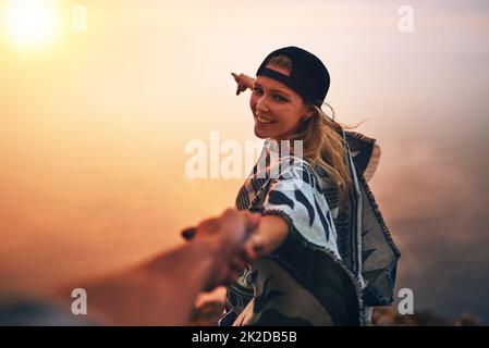 Lets go see whats over there. Portrait of a happy young hiker pointing out a foggy view while holing her boyfriends hand. Stock Photo