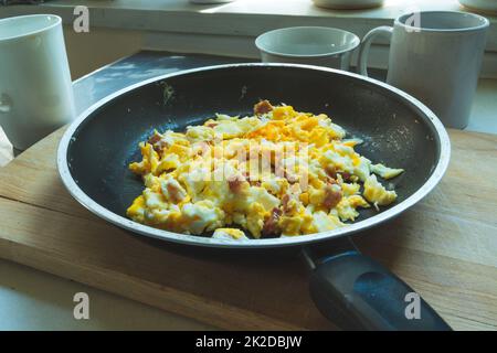 Fresh scrambled eggs with bacon in a pan Stock Photo