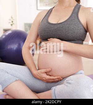 Keeping her body fit for her baby. Cropped shot of a pregnant woman exercising at home. Stock Photo