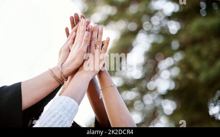 We did it. Closeup shot of a group of students giving each other a high five on graduation day. Stock Photo