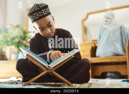 Children more than ever, need opportunities. Shot of a young muslim boy reading in the lounge at home. Stock Photo