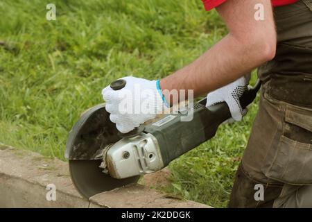 Construction worker cutting concrete plate for fence foundation using a ...