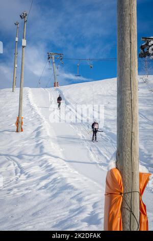 Woman with ski and man with snowboard using ski lift Stock Photo