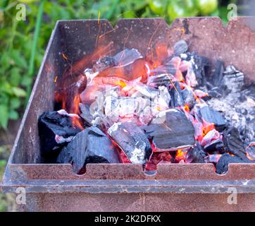 Hot coals with sparks in the grill close-up, natural background, outdoors, in summer Stock Photo
