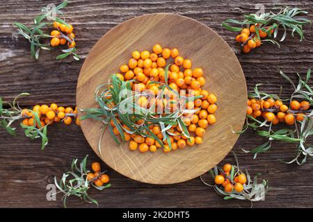 Sea buckthorn background. Organic ripe sea buckthorn on old wooden plate, rustic background. Top view Stock Photo