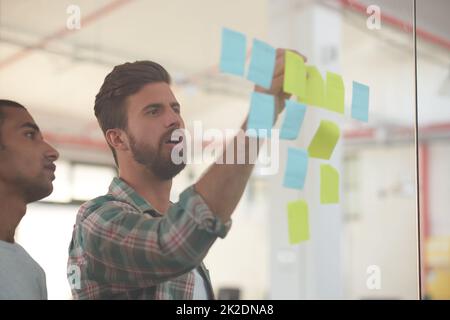 Plans in progress. Shot of two colleagues discussing ideas together on sticky notes. Stock Photo