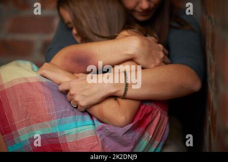 Itll be okay.... Abused woman embracing her frightened daughter. Stock Photo