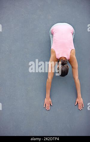 Stretching away the stress. High angle view of an attractive mature woman doing yoga outdoors. Stock Photo