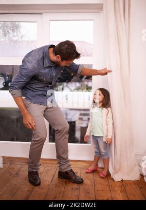 Found you. A handsome young father playing hide and seek with his young daughter. Stock Photo