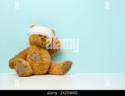children's toy teddy bear sits with a bandaged head. Childhood trauma concept Stock Photo