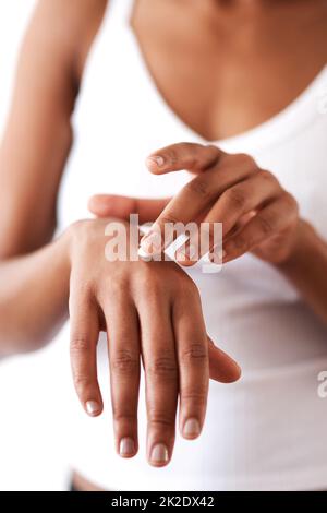 Keeping your hands moisturised is just as important. Studio shot of an unrecognizable woman moisturising her hands. Stock Photo