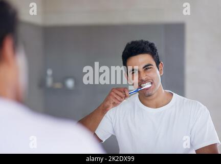 He brushes twice daily for optimal oral health. Shot of a young man brushing his teeth at home. Stock Photo