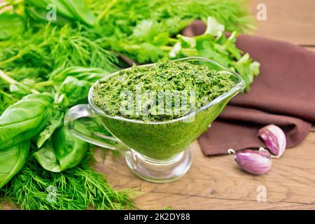 Sauce of spicy greens in gravy boat on old wooden board Stock Photo