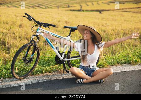 Happy woman with a bicycle on side of the road Stock Photo