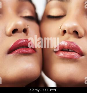 The perfect lip colour to go with their complexion. Studio shot of two beautiful young women posing against a grey background. Stock Photo