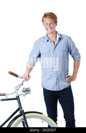 Who needs modern modes of transportation. A handsome young red-headed man standing next to an old-fashioned bicycle with his hand on his hip. Stock Photo