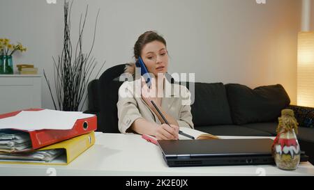 Female manager making business notes on notebook, working alone in office. Stock Photo