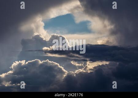 An opening in storm clouds showing blue sky beyond. Stock Photo