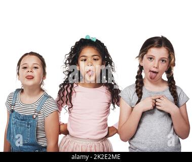The best part of friendship is having lots of fun. Studio portrait of a group of three girls sticking out their tongues against a white background. Stock Photo