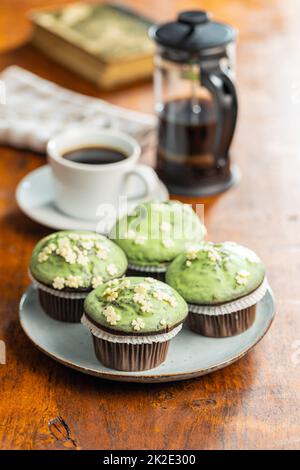 Sweet muffins with pistachio icing. Sweet dessert on wooden table. Stock Photo