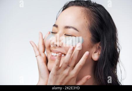 Give your skin the treatment it deserves. Studio shot of a beautiful young woman wearing under-eye patches. Stock Photo