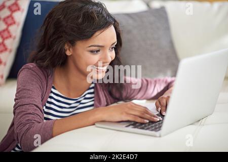 Its a wireless and worry free weekend. Shot of a young woman using her laptop while sitting on the floor. Stock Photo