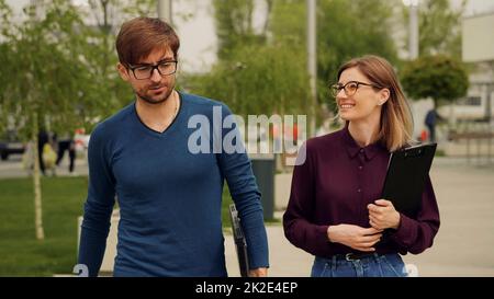 Business people walking together out of office building and discussing succesful business project. Friendly atmosphere outdoor. Stock Photo
